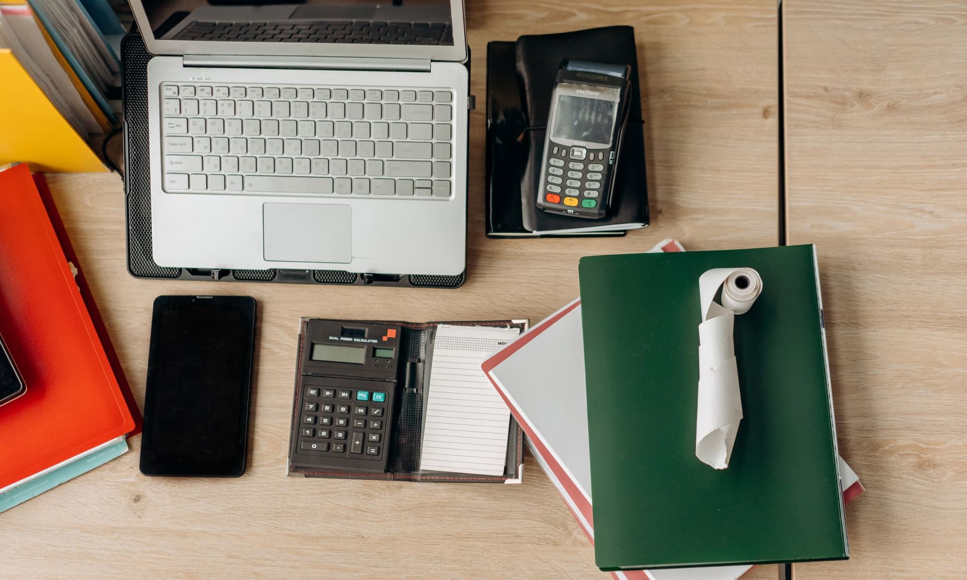 A tidy office desk with a laptop, calculator and document folders